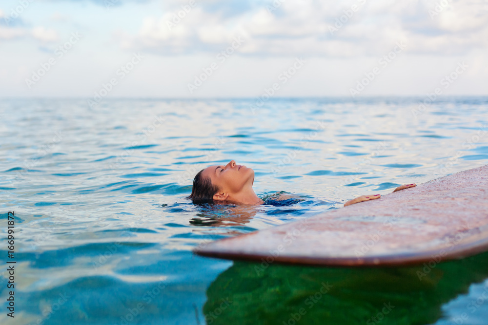 快乐的女人在冲浪前玩得很开心。冲浪女孩拿着冲浪板，看着日落的天空。人们在冲浪