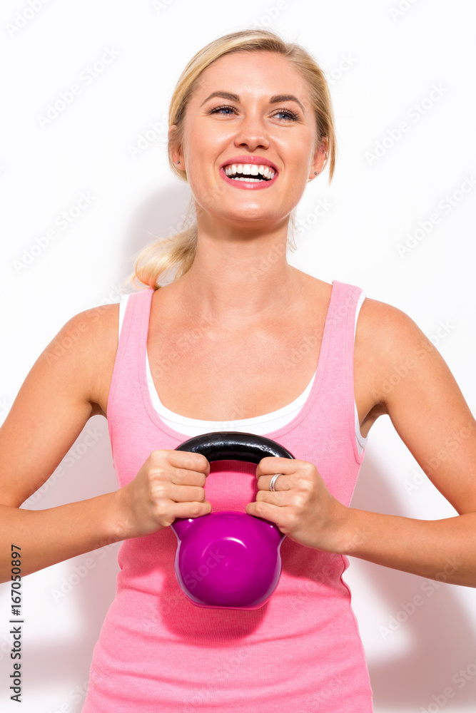 Happy young woman working out with a kettlebell