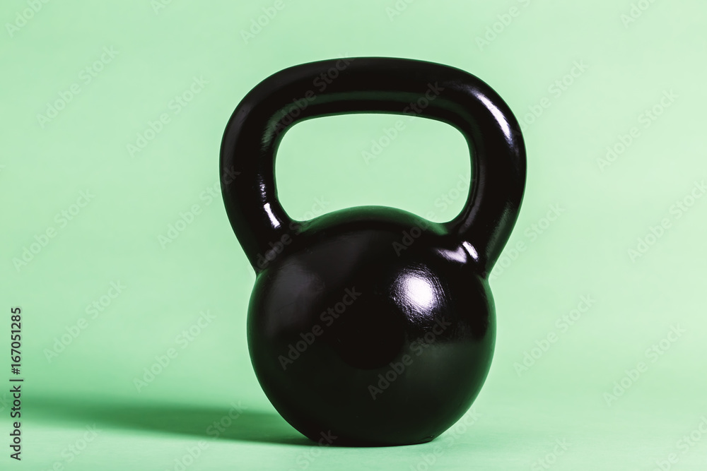 Black cast iron kettlebell on a green background