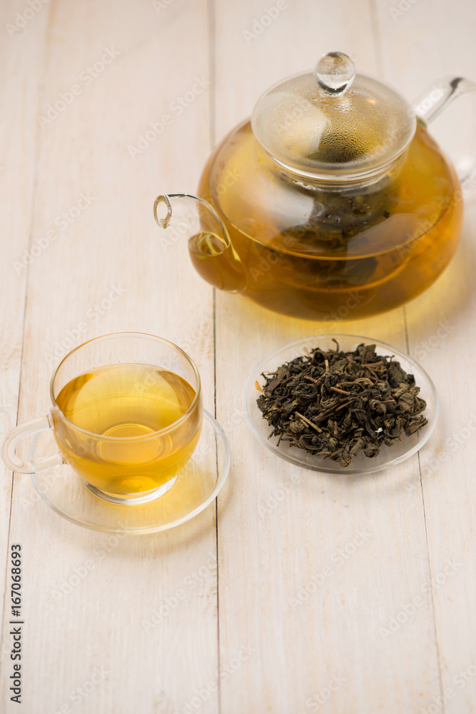 Pouring tea. Cup of hot tea and tea leaf on the wooden table