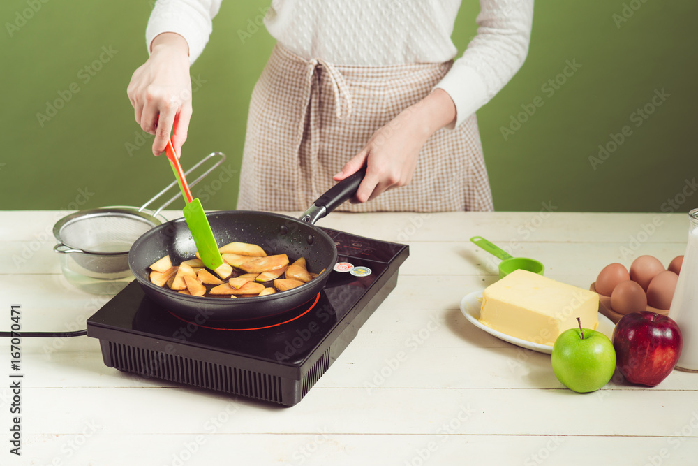 家里的妻子穿着围裙做。烹饪苹果蛋糕的步骤。切青苹果。