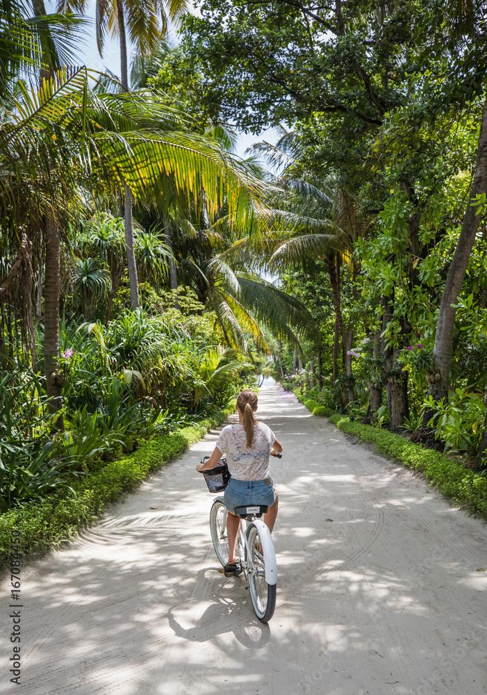 Young girl bicycling on a tropical island.