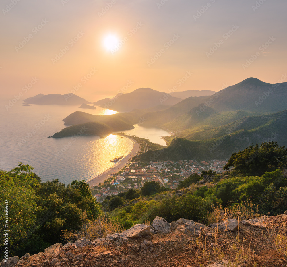 日落时的山景。美丽的海景，有山、水、岛屿、城市和橙色的天空