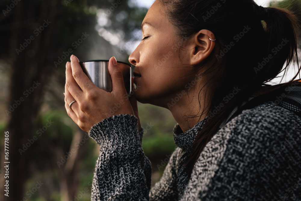 年轻的亚洲女人在户外喝咖啡