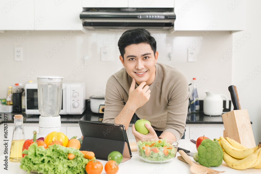 年轻的亚洲英俊男子在家厨房准备食物