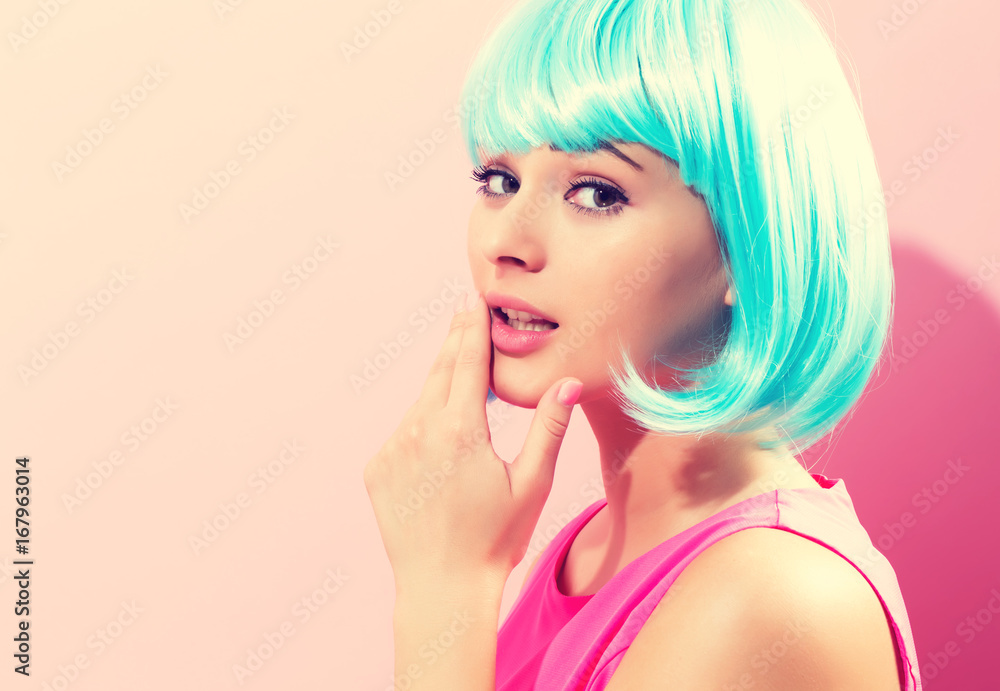 Beautiful woman in makeup with a bright blue wig on a pink background