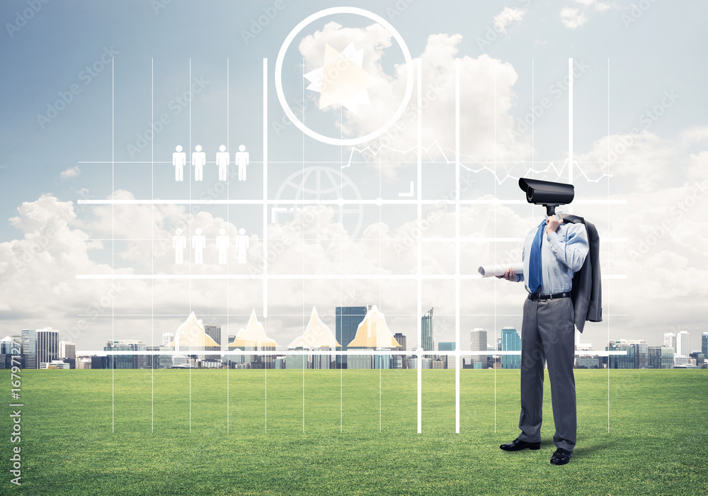 Camera headed man standing on green grass against modern citysca