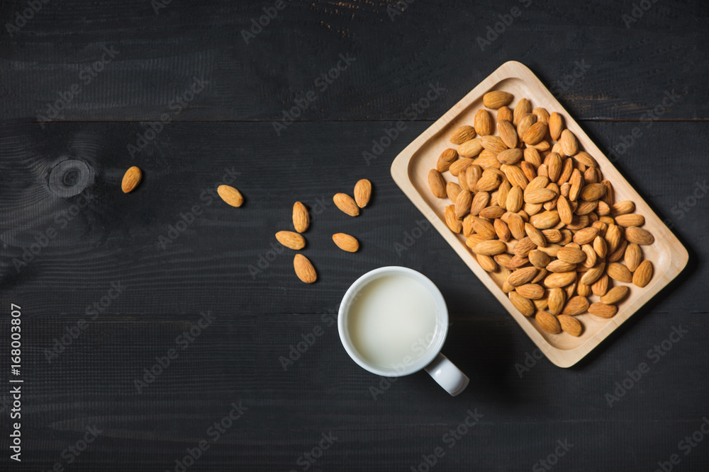 Almond milk in glass with almonds on  black wooden table