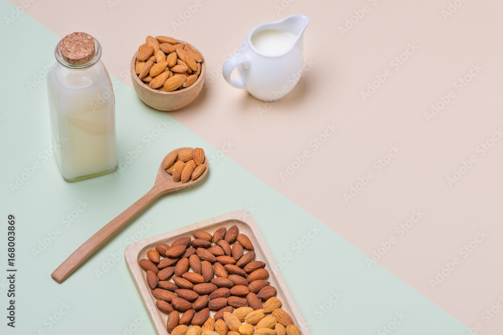 Almonds and milk bottle on light background. Almond nuts in spoon.