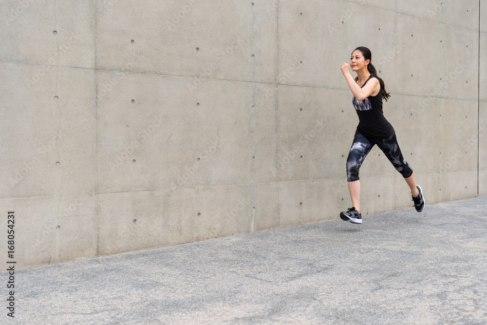 young female jogger jogging on gray background