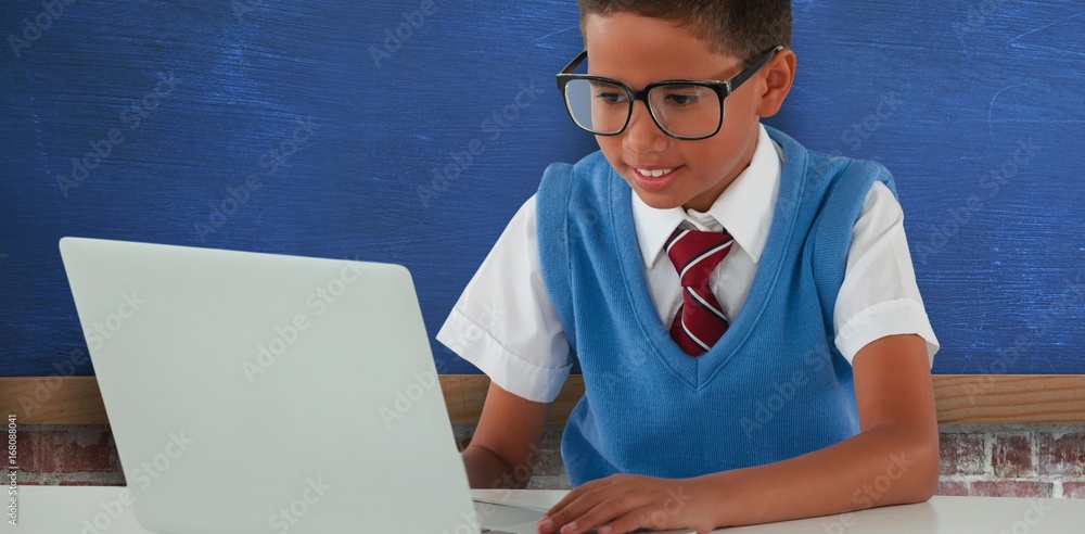 Composite image of schoolboy using laptop at table