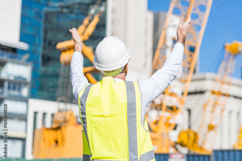 Senior foreman in glasses doing his job at building area on sunny day