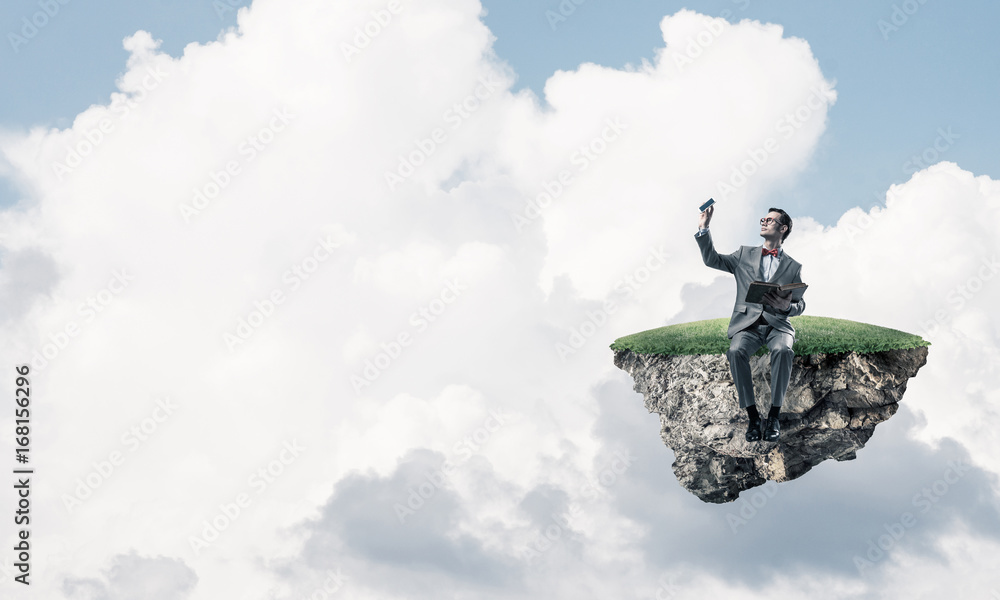 Young businessman or student floating in sky and studying the sc