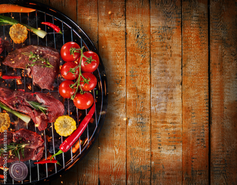 Top view of fresh meat and vegetable on grill placed on wooden planks