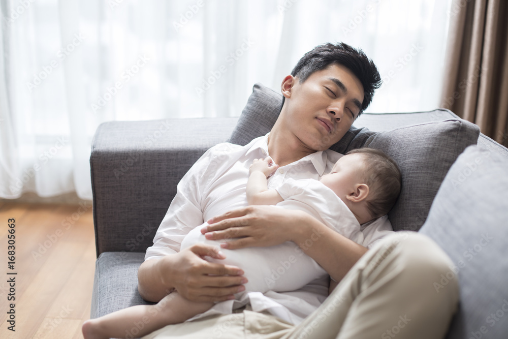 年轻的父亲和男婴睡在沙发上