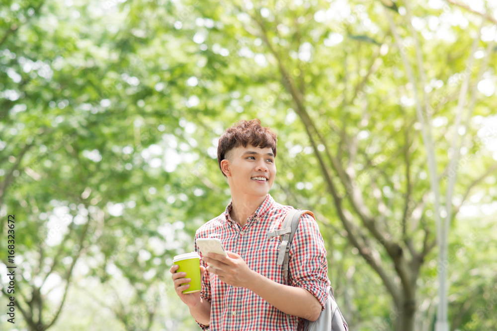 Handsome college student with backpack standing in profile and looking at camera with toothy smile, 