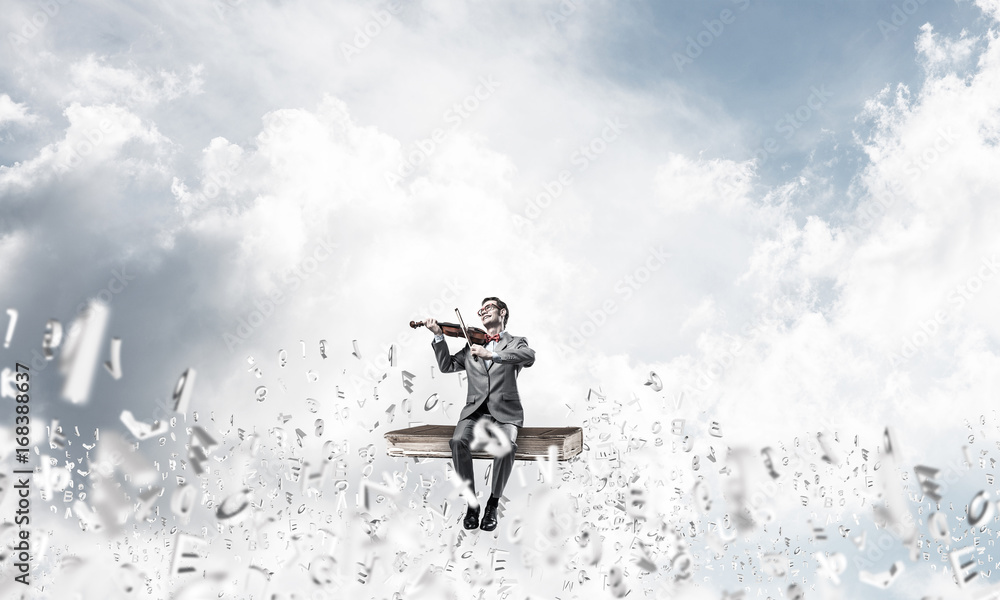 Handsome violinist play his melody and symbols fly around in air