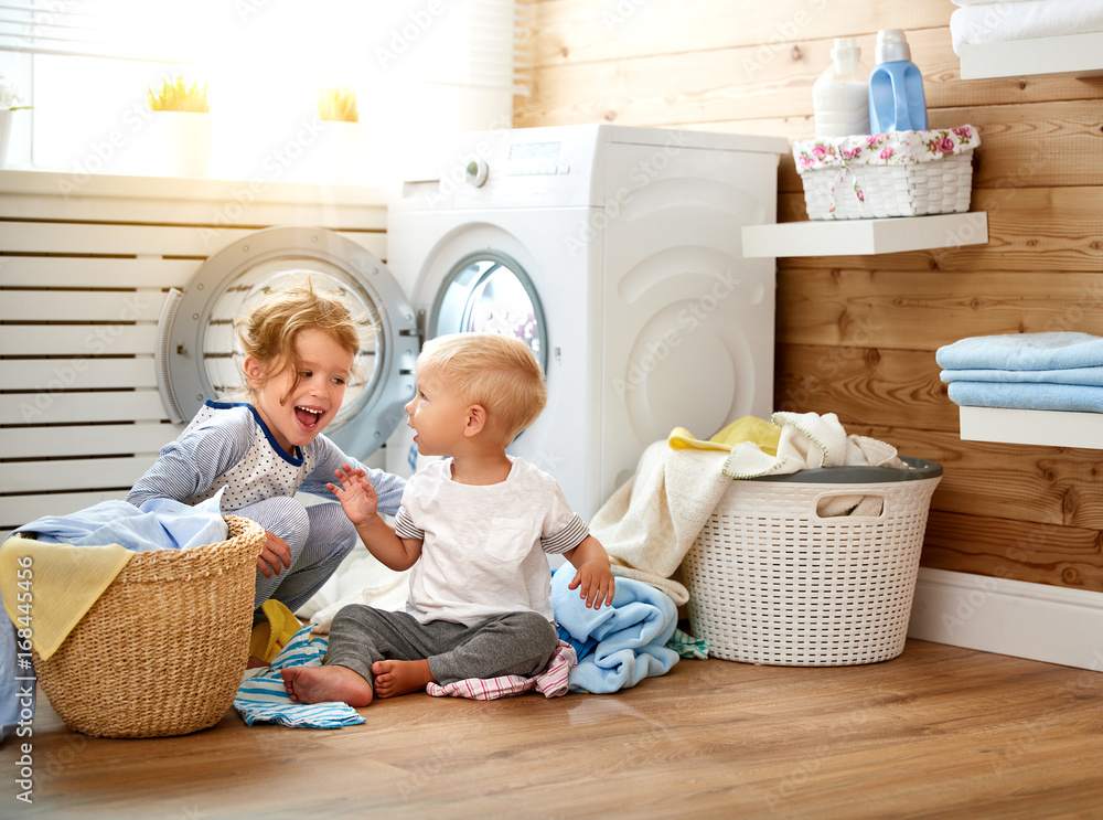 Happy children boy and girl in   laundry load washing machine.