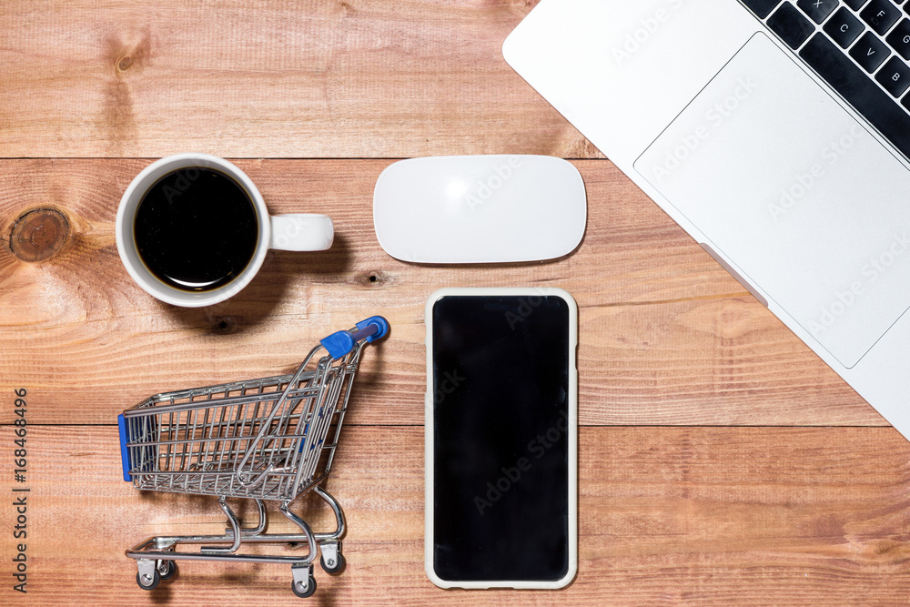 Trolley, keyboard, mobile and credit cards for online purchasing on stone background top view mockup