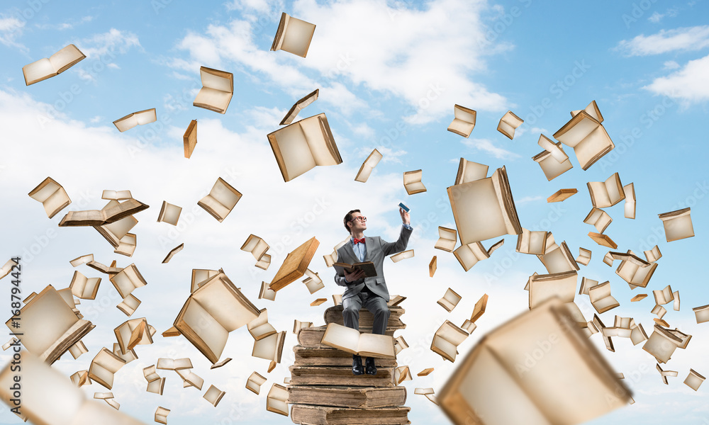 Young businessman or student studying the science and books fly around