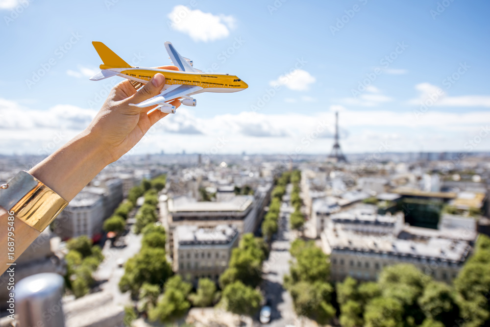 在巴黎城市景观背景下拿着一架玩具飞机。空中连接和旅游概念