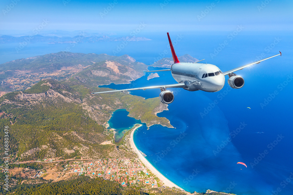 Airplane is flying over amazing islands and mediterranean sea at bright day. Landscape with white pa