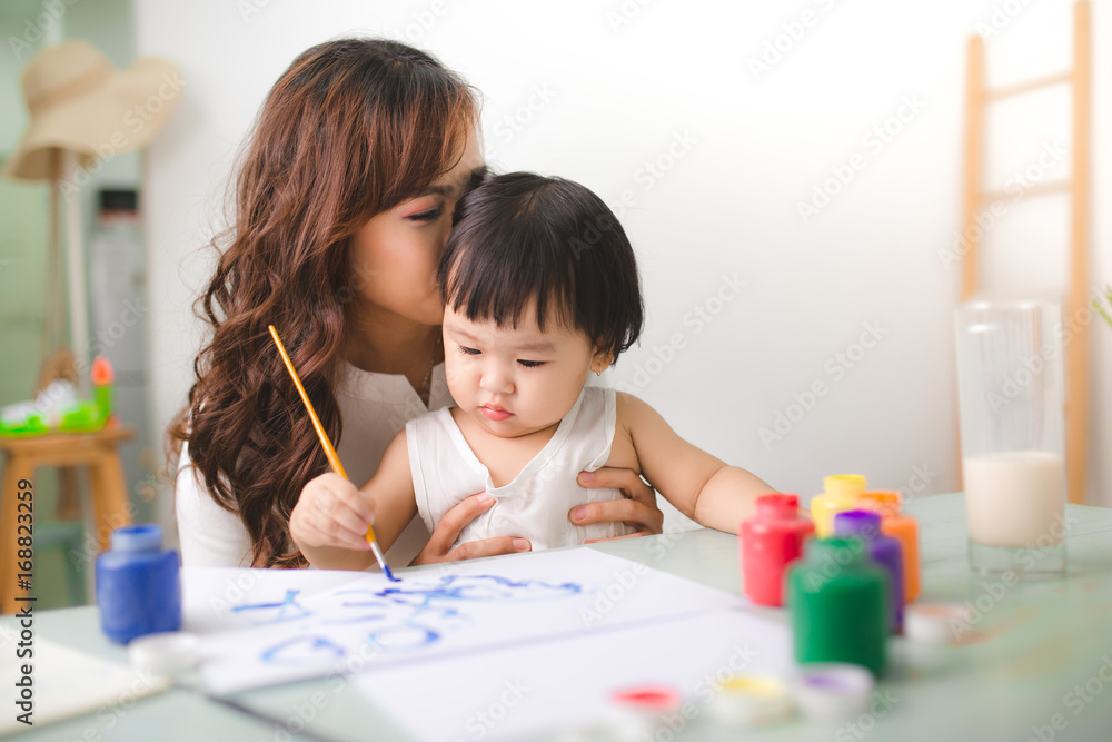 幸福的家庭，母亲和女儿一起画画。亚洲妇女帮助她的小女儿。