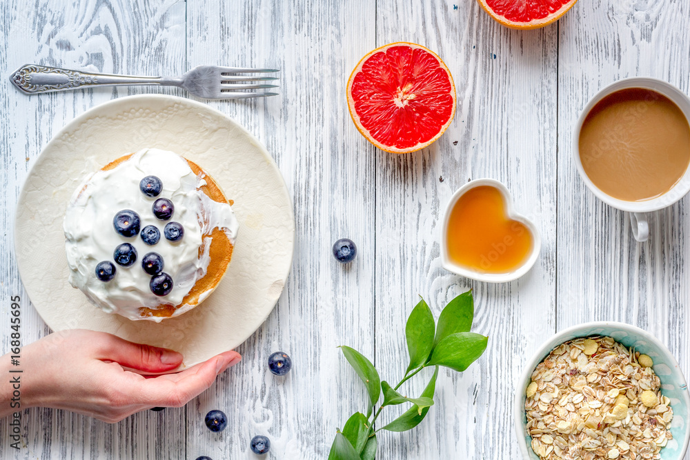 Breakfast concept with flowers on wooden background top view