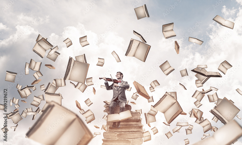 Handsome violinist sitting on book and play his melody