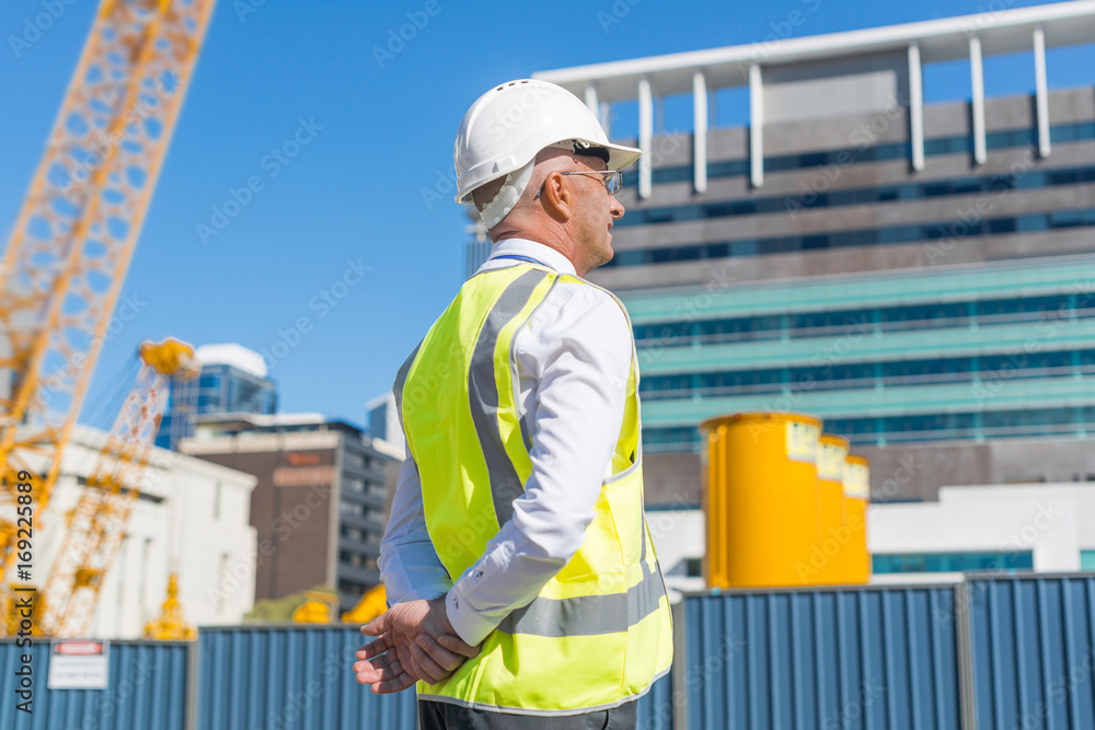 Senior foreman in glasses doing his job at building area on sunny day