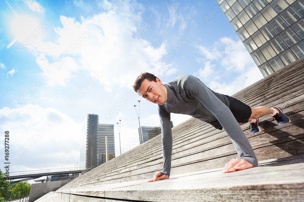 Sportsman doing push-ups outdoors on city stairs