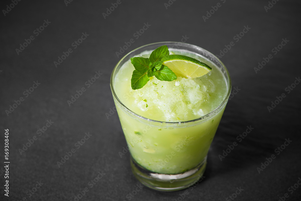 Cocktail juice with lime, mint and ice. Bar drink accessories on black table background.