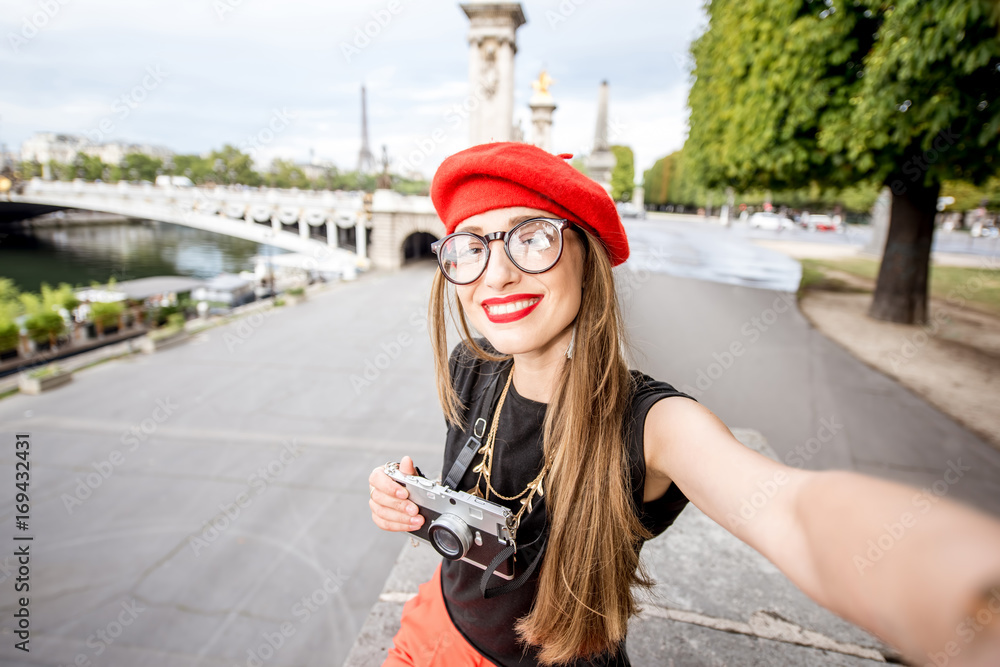 Young woman tourist with red cap making selfie portrait traveling in Paris