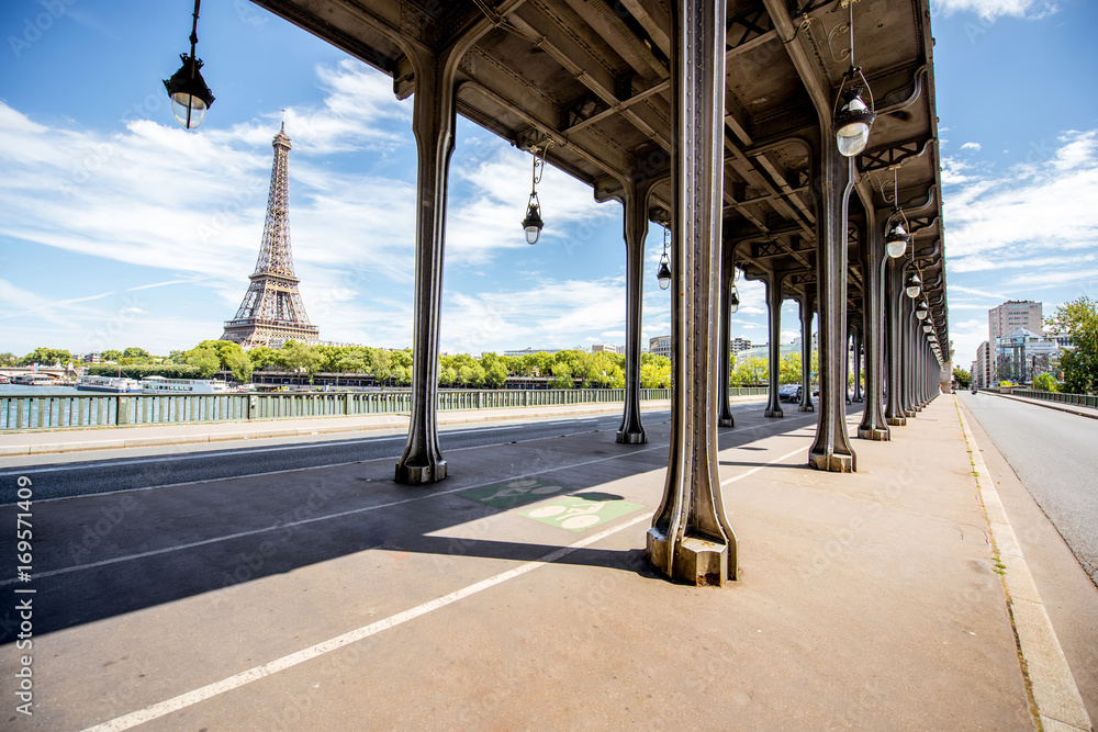 Cityscape view on the old iron bridge with Eiffel tower on the background during the sunny day in Pa