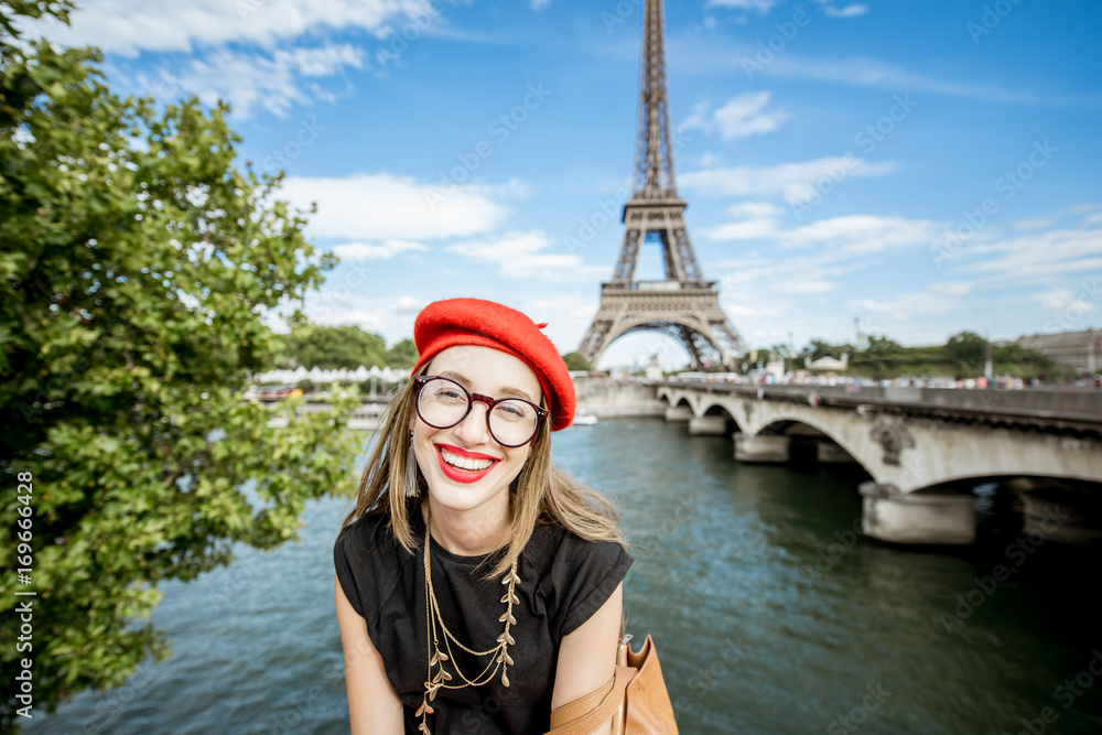 Portrait of a young woman tourist in red cap in front of the Eiffel tower in Paris