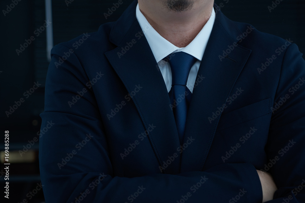 Part of man body side folded his arms in black suit on black background, business concept .