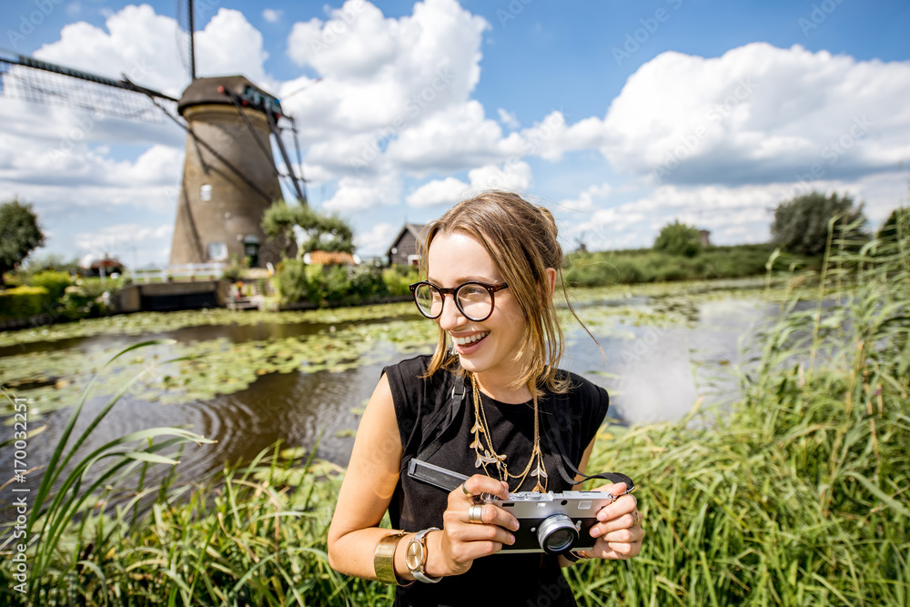 Portrait of a young woman tourist standing with photo camera on the beautiful landscape background w