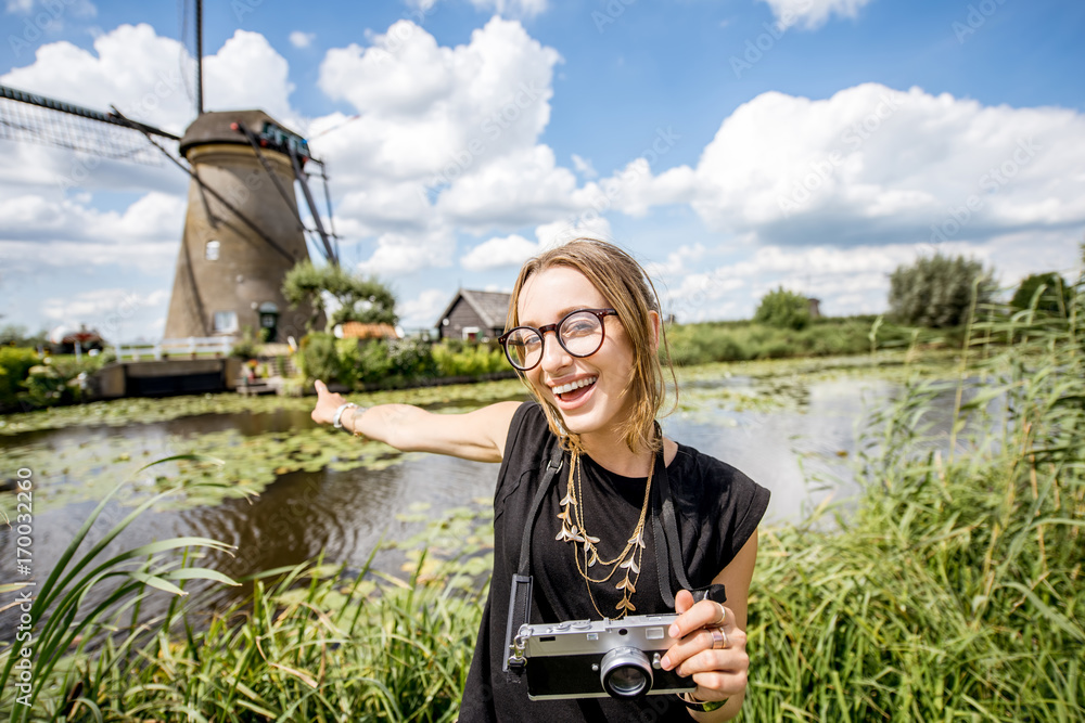 Portrait of a young woman tourist standing with photo camera on the beautiful landscape background w