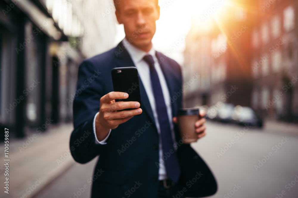 Young executive reading messages on his cellphone in the city