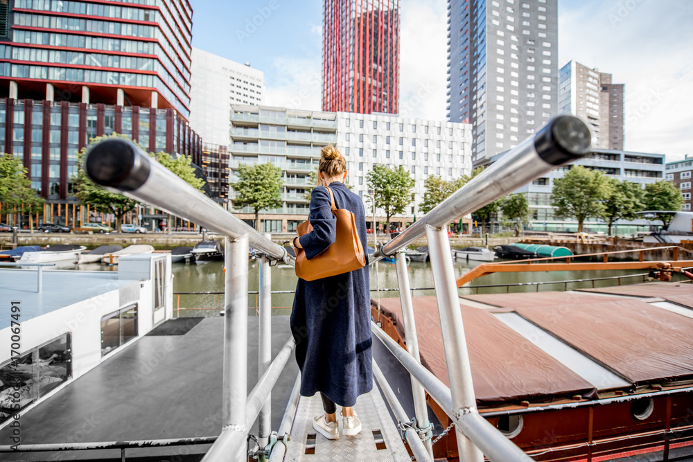 Woman walking back on the bridge at the modern district with slyscrapers in Rotterdam city