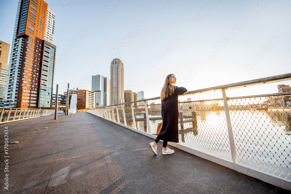 罗特丹市早上站在桥上欣赏现代城市景观的女人