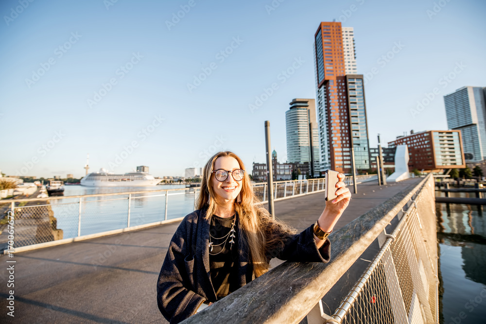 Woman standing with phone on the footbridge at the modern residential district during the morning in