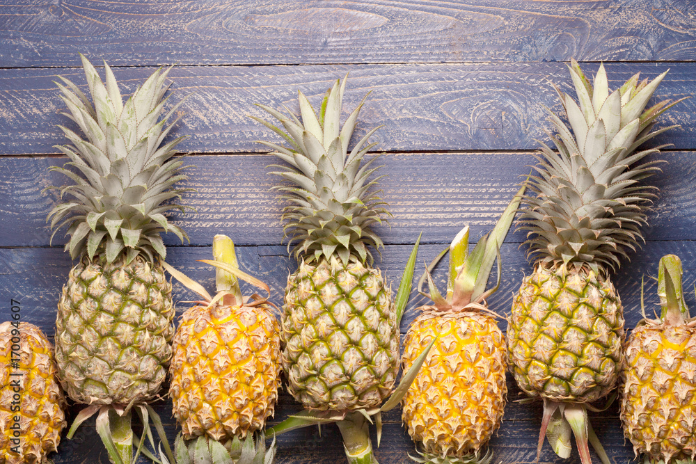 Row of pineapples on wood background.