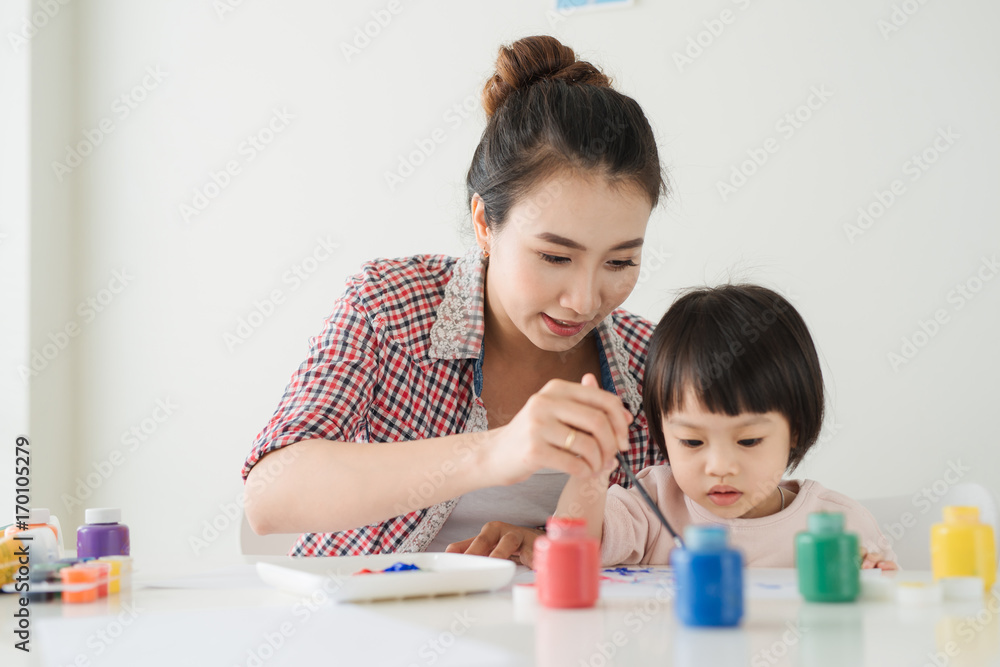 一个幸福的家庭正在画画。妈妈帮女儿画画