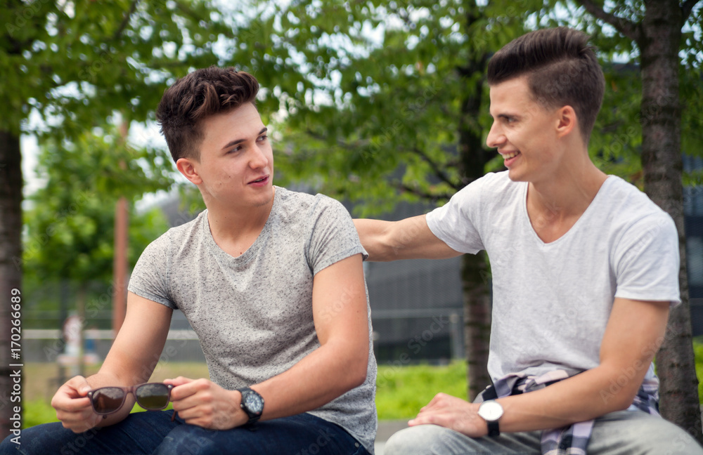 Two friends sitting on bench in town and talking, best friend