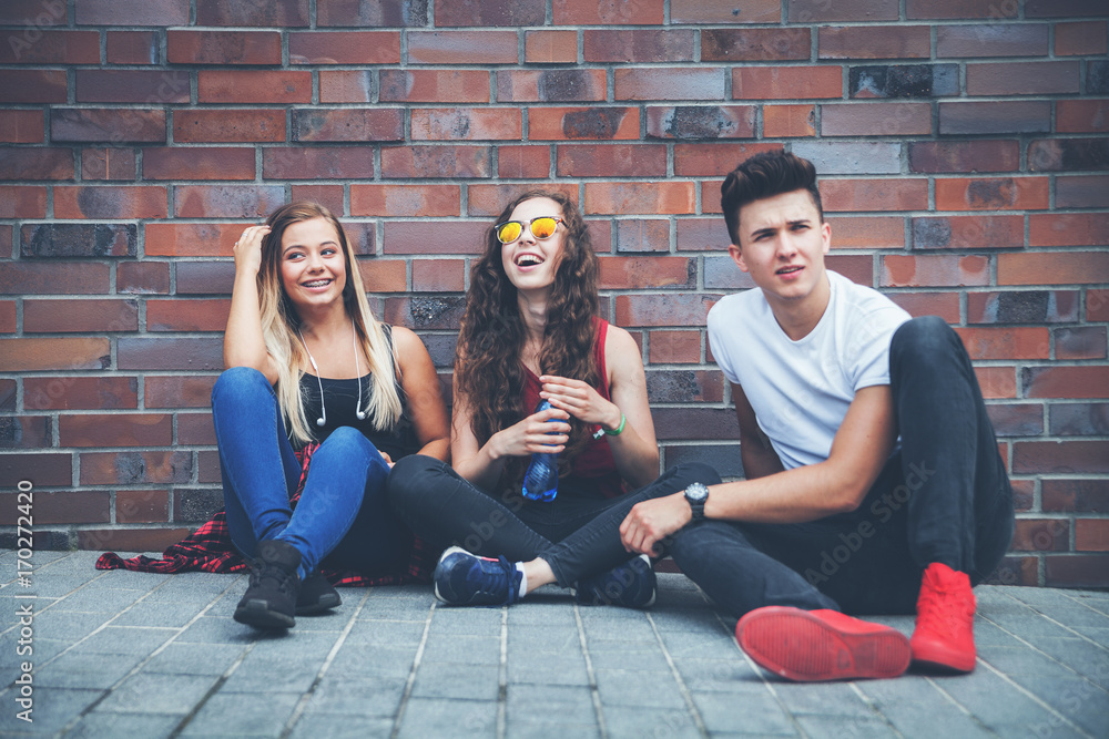 Group of young friends sitting on street and talking