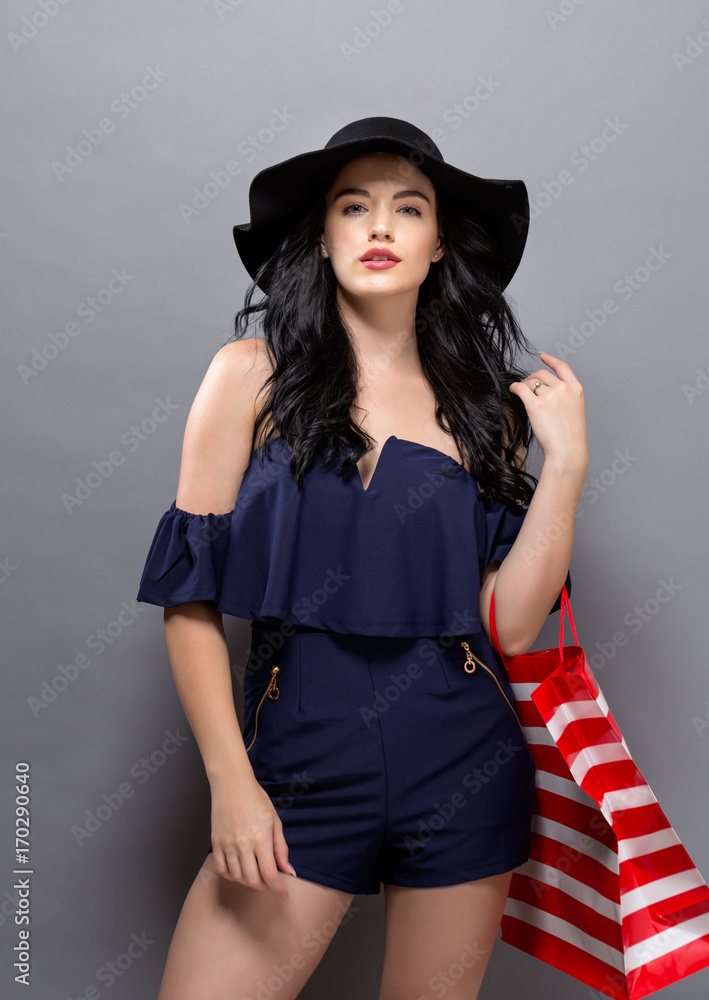 Young woman holding a shopping bag on a gray background