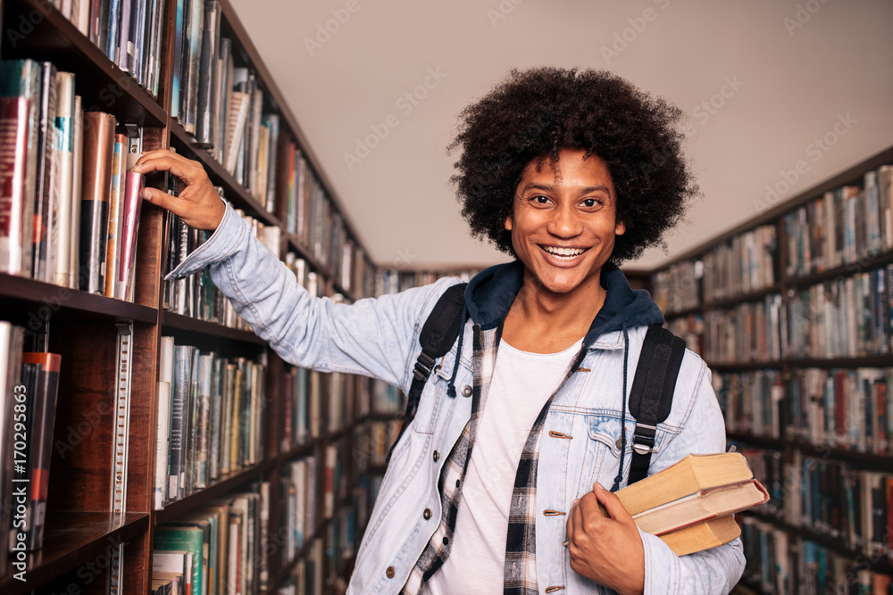 University student standing by bookshelf in the library