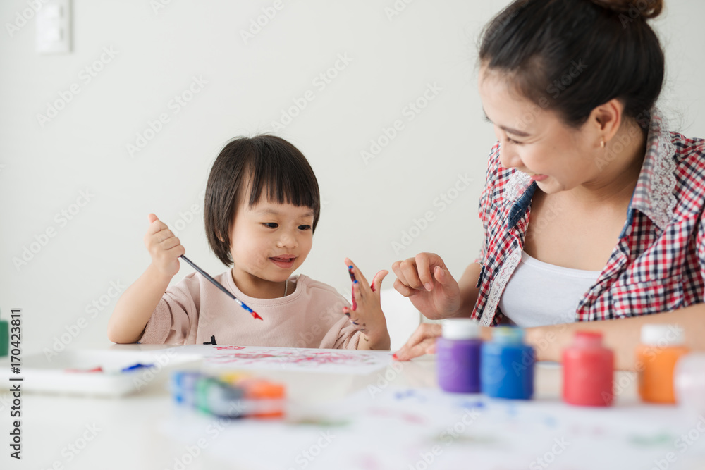 一个幸福的家庭正在画画。妈妈帮女儿画画