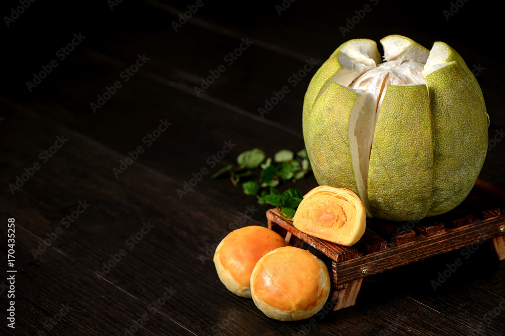 yolk pastry (egg yolk shortcake) and peeled grapefruit on wooden table isolated on black background